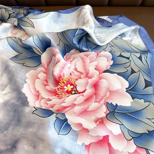 Elegant silk scarf featuring vibrant pink peony patterns with soft satin luster and blue leaves