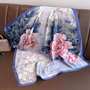 Elegant silk scarf with pink peony and blue floral pattern on leather background