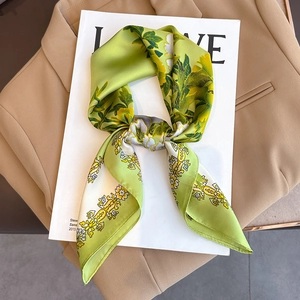Eleganter Seidenschal mit Blumenmuster in Grün und Gelb auf einem beigen Blazer