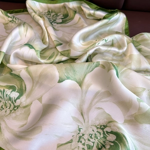 Elegant square silk scarf with vibrant green floral print on smooth glossy fabric
