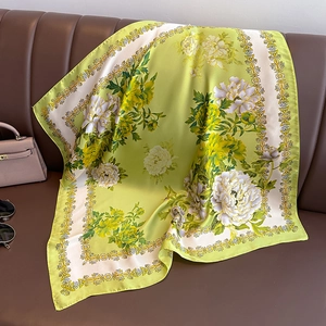Eleganter grüner Seidenschal mit Pfingstrosenmuster auf einem Ledersofa drapiert