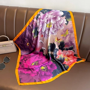 Floral print silk scarf with purple peonies and butterfly on a brown leather sofa