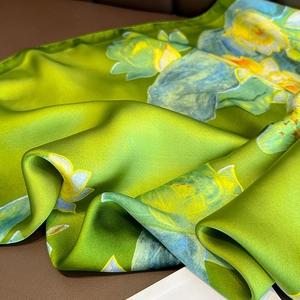 Green silk-like scarf with lotus floral print showing elegant drapes and smooth satin texture