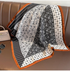 Detailed pattern of a paisley silk-like square scarf on a leather sofa with fashion accessories