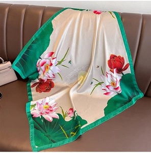 Detail of champagne silk scarf featuring lotus patterns on a brown leather surface