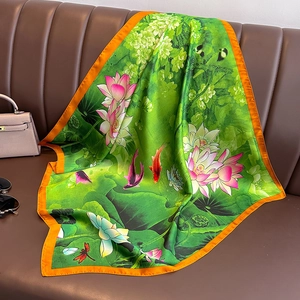 Eleganter Lotus Seidenschal mit Seerosen-Druck in Grün und orangefarbenem Saum auf Sofa