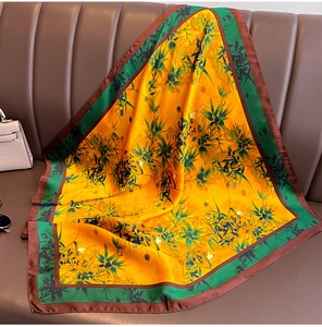 Détail de texture d'un foulard carré en soie jaune avec feuilles de bambou sur canapé