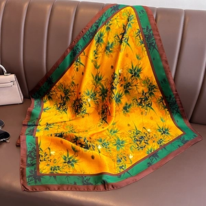Élégant foulard en soie jaune avec imprimé bambou vert drapé sur un canapé en cuir
