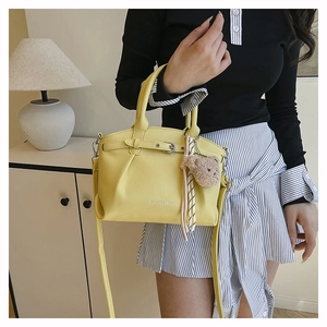 Detail of lemon yellow bucket bag with fashion lettering and cute bear charm pendant