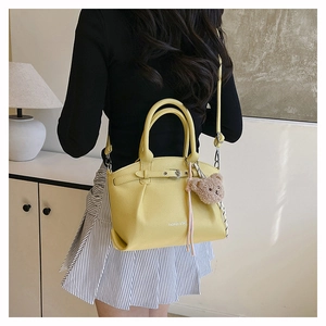 Detail of yellow pebbled leather tote bag with FASHION & BAG logo and teddy bear charm