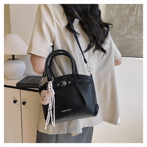 Detail of black lychee grain leather tote with silver buckles and plush bear accessory