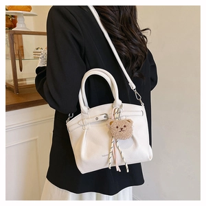 Close-up of white lychee pattern crossbody bag with cute plush bear and striped rope detail