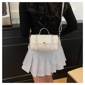 Close-up of woven flap texture and gold metal clasp on ivory crossbody bag for women