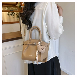 Detail of khaki pebbled leather bucket bag with fashion logo and teddy bear charm accessory
