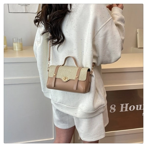 Elegante borsa a tracolla marrone con patta intrecciata indossata da una modella.
