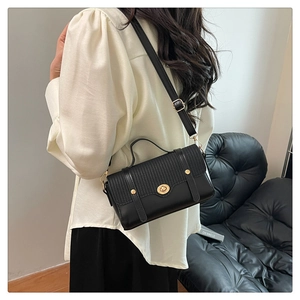 Detail of black patchwork crossbody bag with woven texture and gold twist lock closure