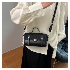 Detailed close-up of a luxury black mixed-texture crossbody bag with golden hardware