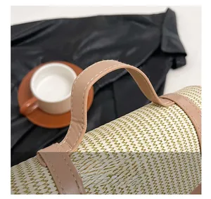 Detail of hand-woven straw tote with premium stitching on leather handles and color contrast