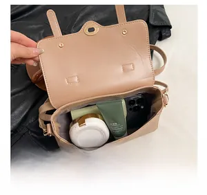 Interior capacity view of beige crossbody bag with phone, cushion, and cream items