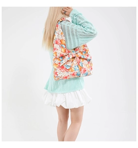 Detailed view of floral shoulder bag with oversized bow on a green knit sweater outfit