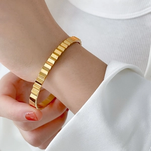 Close-up of pleated 18K gold plated titanium steel bangle with ribbed texture on wrist