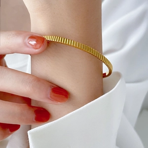 Detail of 18K gold plated bangle featuring vertical pleated texture and glossy finish