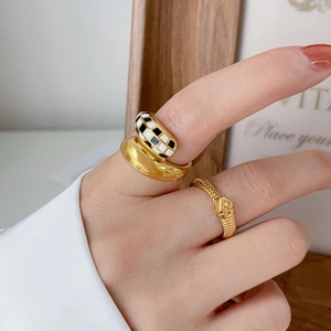 Detalle de anillo de esmalte a cuadros y anillos dorados con textura de serpiente