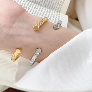 Close-up of gold and silver matelasse quilted bangles on a wrist with a book background