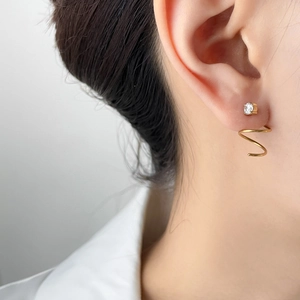 Close-up of gold spiral ear cuff and zircon stud earring set on a female model