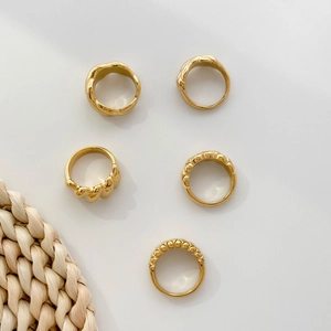 Primer plano de 5 anillos dorados con texturas onduladas y diseño retro francés minimalista