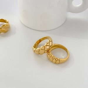 Primer plano del anillo dorado con diseño acolchado y texturas metálicas finas