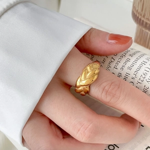 Detalle de anillo trenzado dorado combinado con camisa blanca y fondo de libro retro