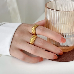 Primer plano de anillos croissant dorados usados en la mano sosteniendo un vaso estriado