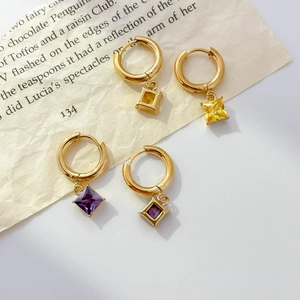 Golden hoop earrings with square yellow and purple cubic zirconia on vintage book pages