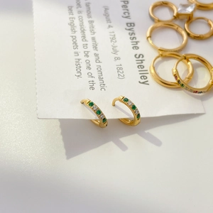 Detail of small gold hoops featuring alternating green and white cubic zirconia stones