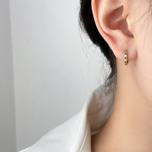 Minimalist gold hoop earring featuring alternating green and white cubic zirconia accents