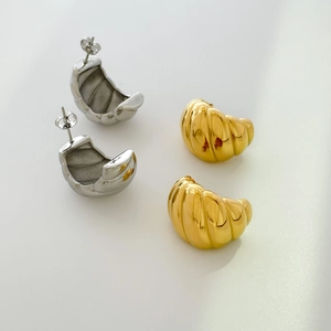 Detailed view of gold and silver croissant dome stud earrings with ribbed metal texture