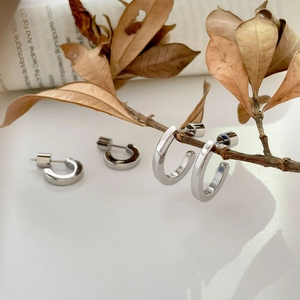 Polished silver C-shaped chunky hoop earrings styled with vintage paper and autumn decor