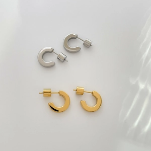 Flat lay of polished C-shaped hoop earrings in gold and silver finish with secure backings