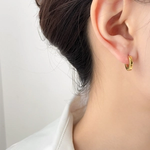 Close-up of a model wearing a polished gold geometric C-shaped hoop earring on ear