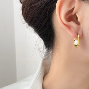 Elegant gold geometric C-shape stud earrings with white pearl inlay on female model