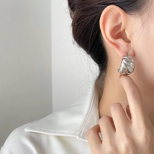 Polished silver croissant C-shaped hoop earrings on a model for a minimalist style