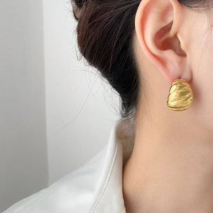 Close-up of golden spiral twisted hoop earrings with a polished metallic finish on ear