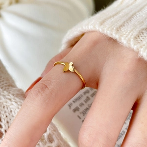 Detail of a 18K gold plated butterfly ring on finger with a cozy knit sweater background