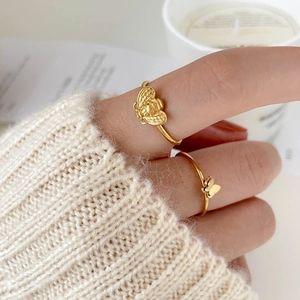 Detailed view of gold plated bee and butterfly rings on hand with cozy home decor