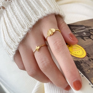 Cute gold bee and butterfly open rings set on a model holding a vintage book
