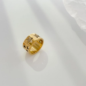 Détail d'une bague large dorée avec découpes en étoile et zircons blancs étincelants