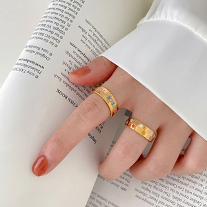 Détail de bagues dorées avec lettres PERFECT colorées et motifs d'étoiles au doigt