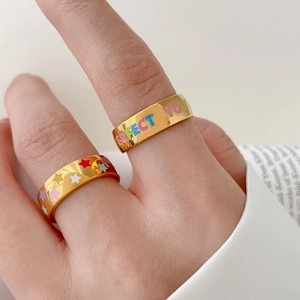 Détail de bagues dorées avec étoiles colorées en émail et texte Perfect You gravé