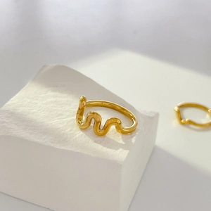 Vue détaillée d'une bague dorée ondulée avec finition miroir sur support